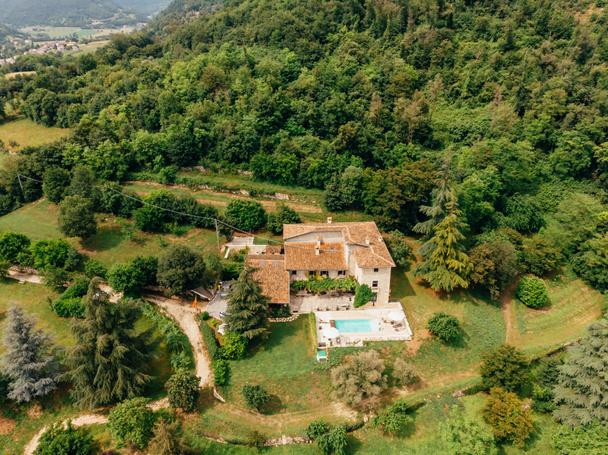 Luftaufnahme eines Paares, das sich am Pool in der Nähe einer Villa in Italien ausruht - Foto, Bild