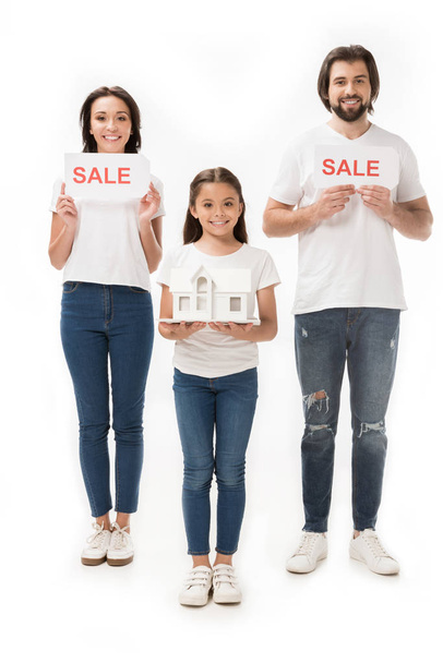 χαμογελώντας οικογένεια με πώληση κάρτες και σπίτι μοντέλο απομονωθεί σε λευκό - Φωτογραφία, εικόνα