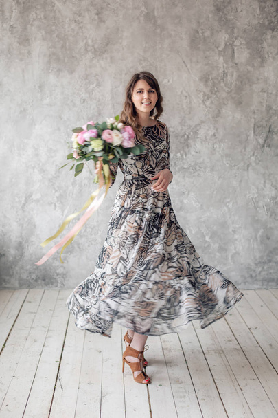 Young beautiful girl in long dress. Girl holds a luxurious summer bouquet. The concept of the celebration or flower shop. looking at the camera - Foto, Bild