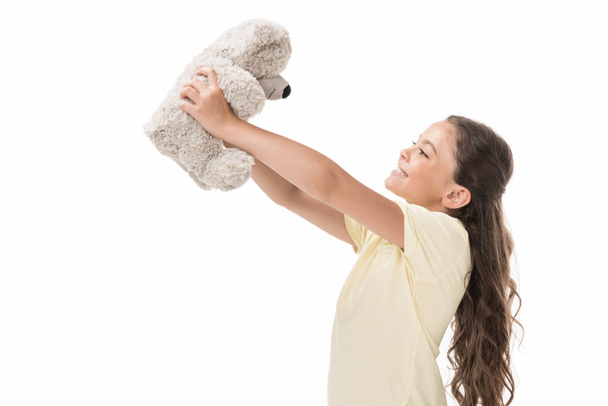 side view of cute smiling kid with teddy bear isolated on white - Фото, изображение