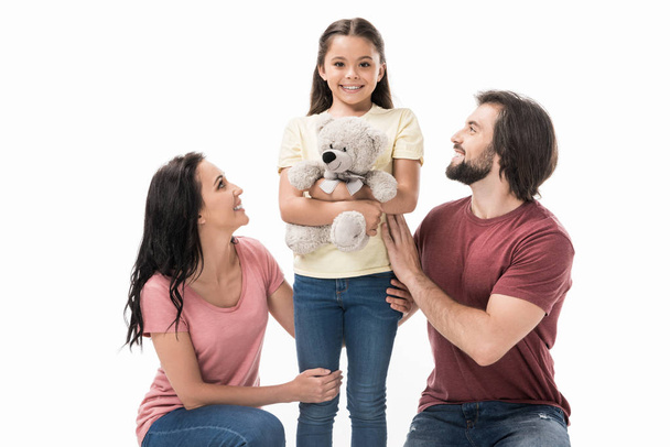 smiling parents and daughter with teddy bear isolated on white - Photo, Image