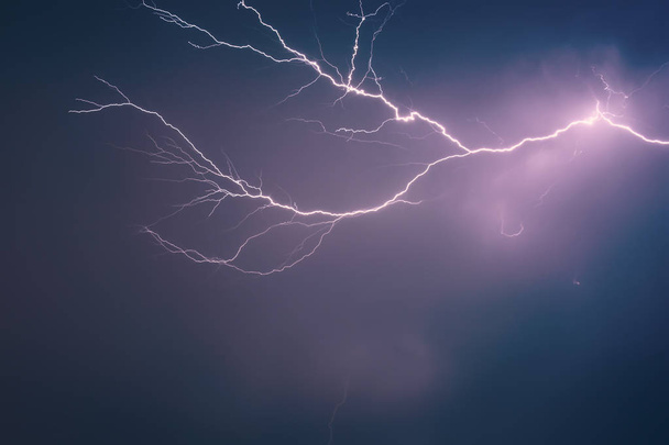 heller Blitz vor dem Hintergrund eines dramatischen Nachthimmels mit Wolken, entladen atmosphärische Elektrizität in der Luft - Foto, Bild
