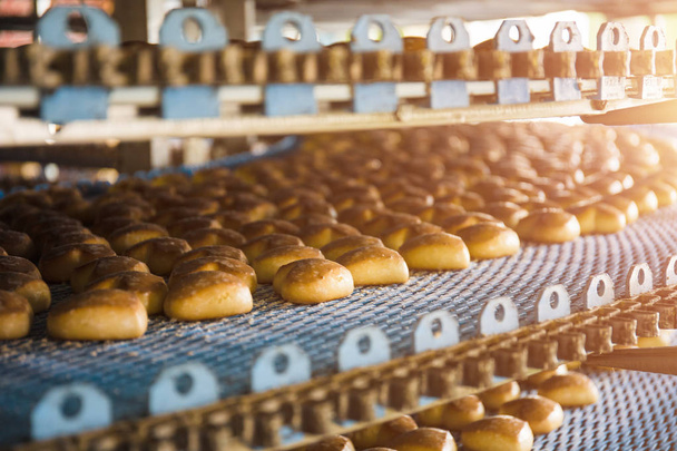 Gâteaux sur bande ou ligne de convoyeur automatique, processus de cuisson dans une usine ou une usine culinaire de confiserie. Industrie alimentaire, biscuits et autres produits à base de pain sucré
 - Photo, image