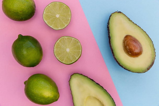 Avocado halves and fresh limes on bright pink background  - Photo, Image