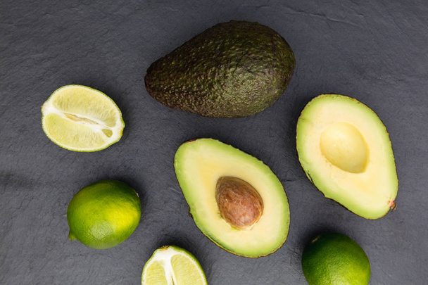 fresh avocado halves and limes on dark background - Photo, Image