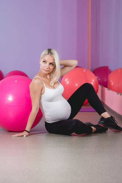 Attractive pregnant womans doing yoga in the gym with dumbbells, healthy lifestyle - Фото, зображення