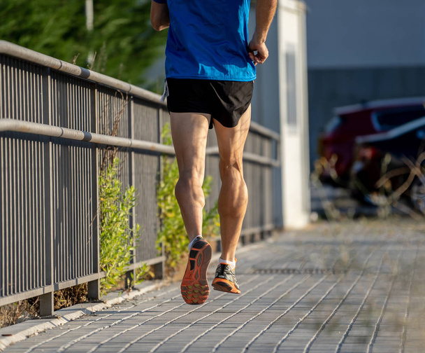 Closeup of sports mans legs running with sport background urban city backdrop in runner fitness concept with copy space - Photo, image