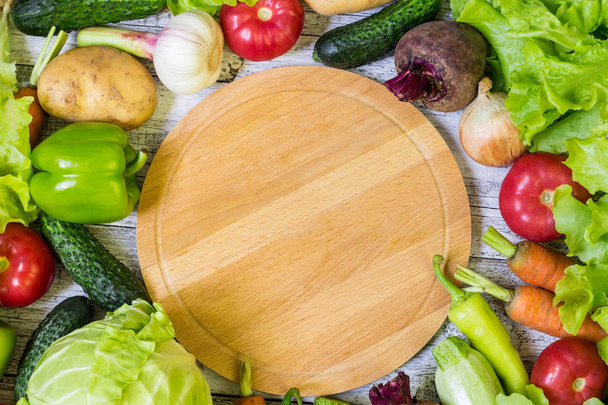 Círculo de tabla de cortar y verduras sobre fondo de madera blanca. Alimentación saludable
. - Foto, Imagen