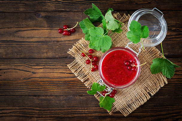 Red currant jam in jar on wooden background. Tasty food. Flat lay. Top view with copy space - Фото, зображення