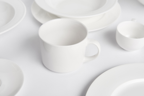 selective focus of various plates, bowl and cup on white table  - Foto, Bild
