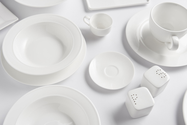 high angle view of different plates, cup, bowl, saltcellar and pepper caster on white table  - Valokuva, kuva