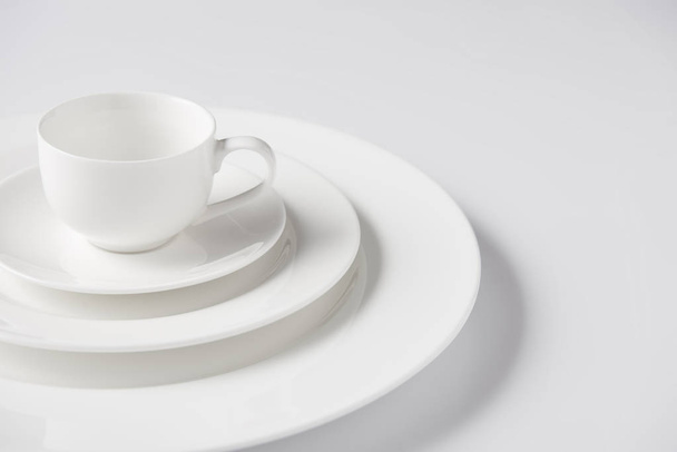 close up image of cup on stack of different plates on white table - Valokuva, kuva
