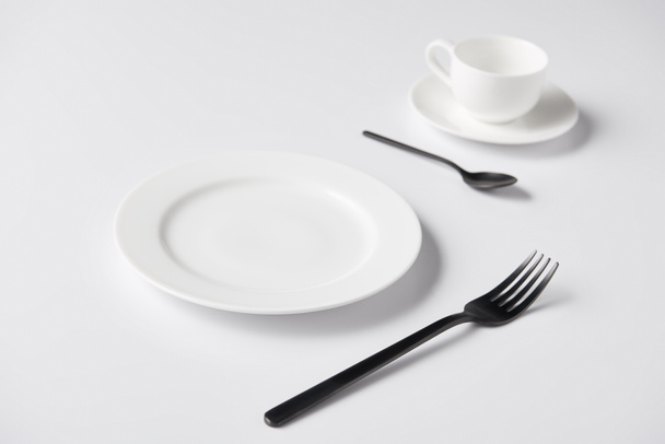 enfoque selectivo de la placa, tenedor, cuchara y taza en la mesa blanca
  - Foto, imagen