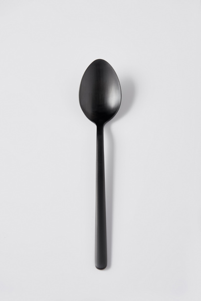 elevated view of black spoon on white background, minimalistic concept - Zdjęcie, obraz