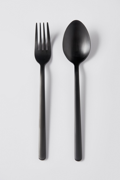 top view of black fork and spoon on white background, minimalistic concept - Foto, Imagem