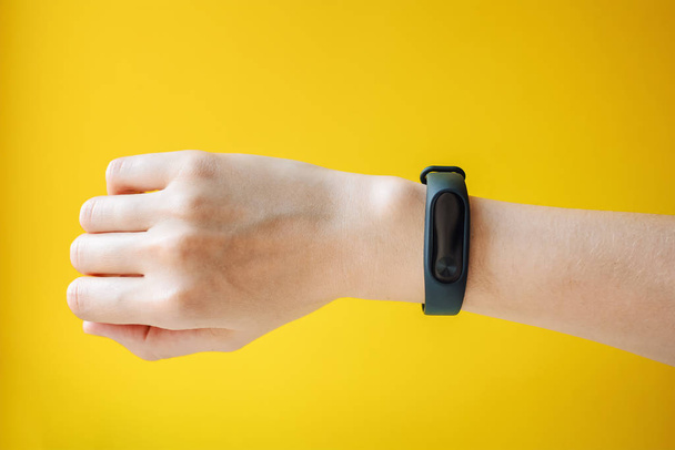 Woman's hand with fitness tracker on yellow background - Foto, Bild