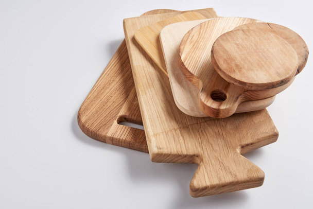 Detail ze zásobníku různé dřevěné krájecí desky na bílém stole - Fotografie, Obrázek
