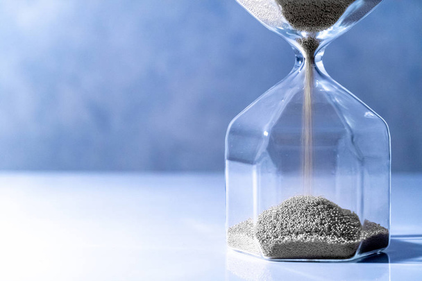 Sliver, písek protéká tvar moderní přesýpací hodiny na bílém stole. Čas předání a málo času. Naléhavost odpočítávací měřič pro obchodní termín koncept - Fotografie, Obrázek