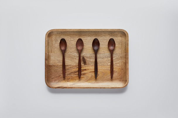top view of wooden tray with wooden spoons on white table, minimalistic concept - Fotografie, Obrázek