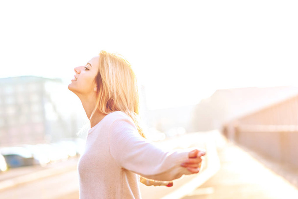 mujer joven con los brazos levantados al aire libre, luz de fondo
  - Foto, imagen