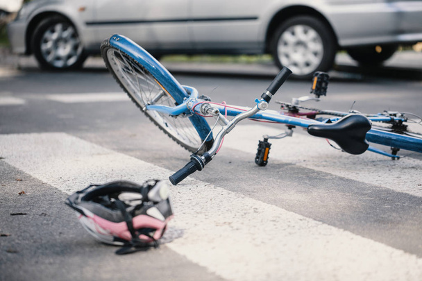 Pink helmet and blue kid's bike on a pedestrian crossing after a crash with a car - Фото, зображення