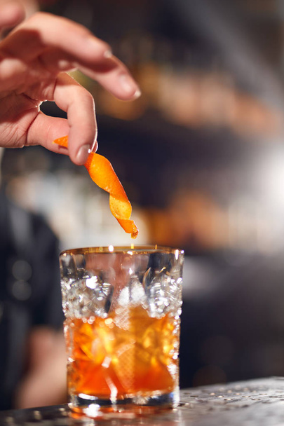 Cocktail. Bartender Preparing Cocktail In Bar. Barman Garnishing Old Fashioned Cocktail With Orange Peel. High Resolution - 写真・画像