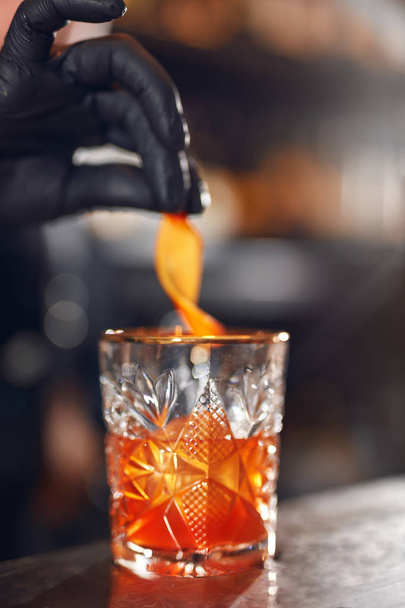 Cocktail. Bartender Preparing Cocktail In Bar. Barman Garnishing Old Fashioned Cocktail With Orange Peel. High Resolution - Фото, зображення