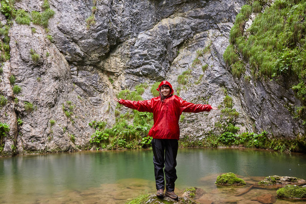 Happy girl in raincoat by a karstic spring after hiking - Foto, afbeelding