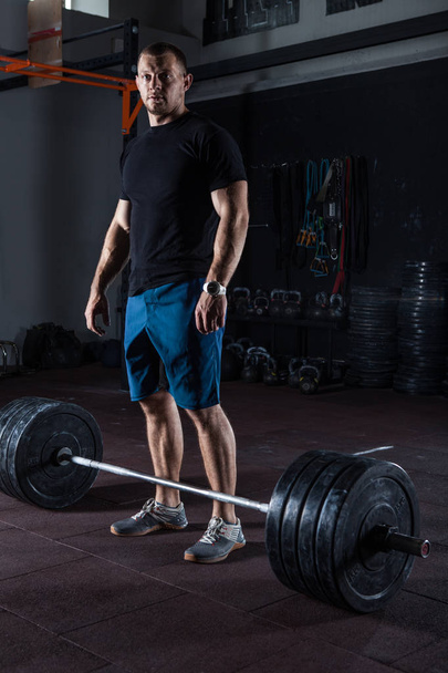 Homem de fitness muscular posando no ginásio em pé na barra antes do exercício
. - Foto, Imagem