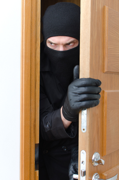 Hombre ladrón en máscara irrumpiendo en la casa
 - Foto, imagen