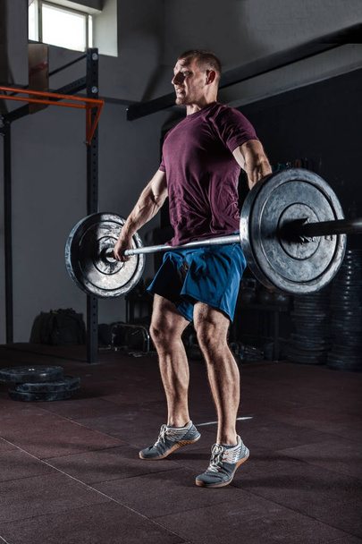 Jeune athlète effectuant des squats aériens avec un haltère lourd à la salle de gym
 - Photo, image