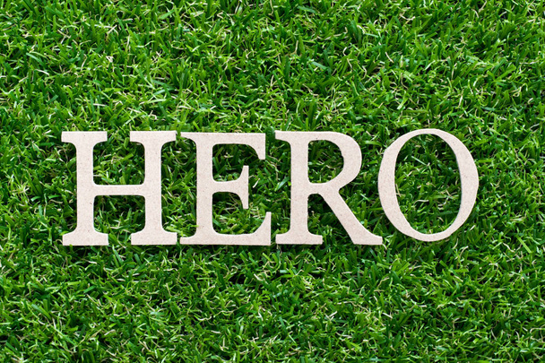 Alfabeto de madeira em herói palavra no fundo grama verde artificial
 - Foto, Imagem