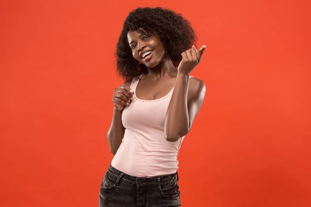 The happy african woman standing and smiling against red background. - Foto, imagen