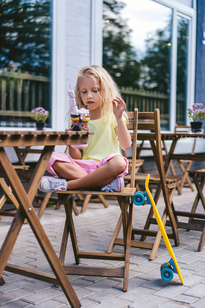 Selektywny fokus koncentruje się małe dziecko z zamkniętymi oczami siedząc przy stole z deser w kawiarni  - Zdjęcie, obraz