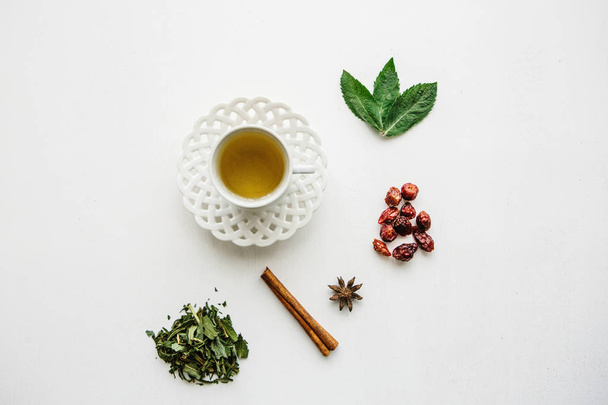 Кружка ароматного и полезного травяного чая. Рядом лежат различные ингредиенты для его приготовления
 - Фото, изображение
