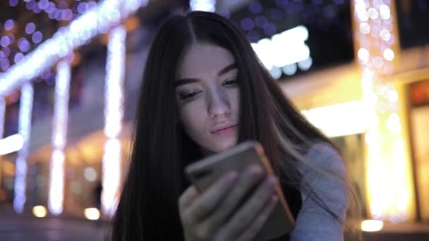 Nő használ smartphone ül az éjszakai város belvárosában - Felvétel, videó