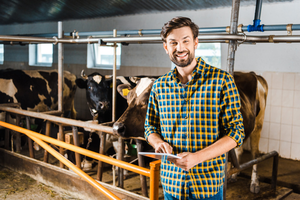 handsome smiling farmer standing with tablet in stable - Fotoğraf, Görsel