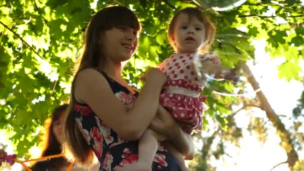 Мама и ее маленькая дочь ловят большие и прозрачные мыльные пузыри в городском парке
 - Кадры, видео