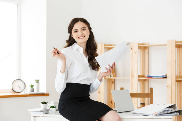 Jovem mulher de negócios feliz ou secretário segurando documento no escritório moderno
 - Foto, Imagem