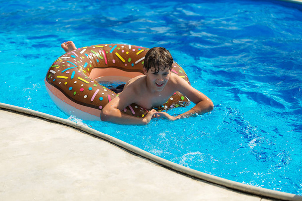 carino ragazzo sportivo nuota in piscina con anello ciambella e si diverte, sorride. vacanza con bambini, vacanze, concetto di fine settimana attivo
 - Foto, immagini