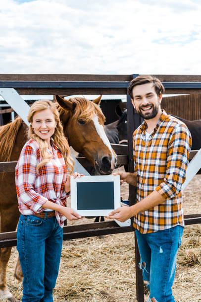 happy couple of farmers holding blackboard in stable - Photo, Image