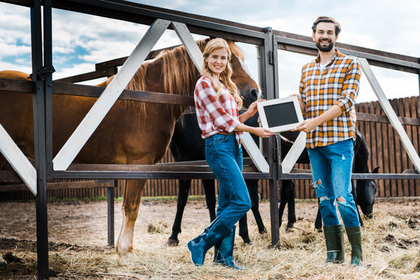 smiling couple of farmers holding blackboard in stable - Photo, Image