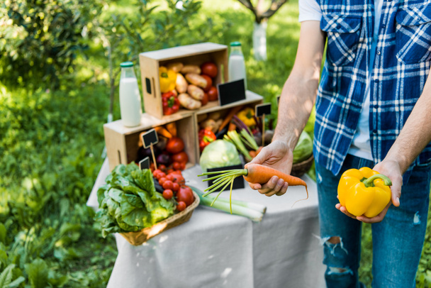viljelty kuva viljelijästä, joka näyttää kypsiä ekologisia vihanneksia viljelijämarkkinoilla
  - Valokuva, kuva
