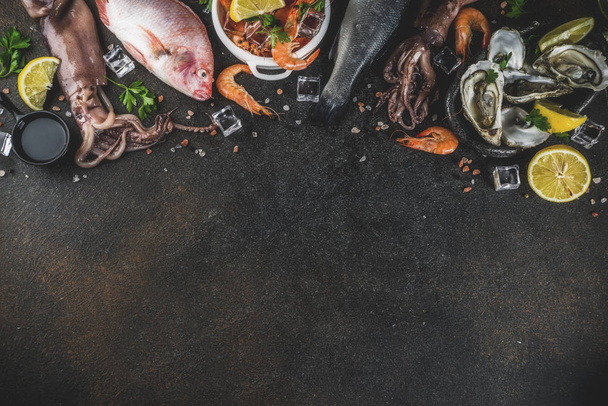 Fresh raw seafood squid shrimp oyster mussels fish with spices of herbs lemon on dark rusty background copy space top view - Foto, Bild