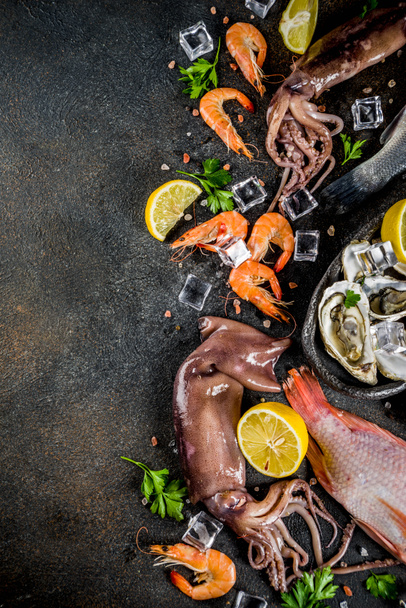 Fresh raw seafood squid shrimp oyster mussels fish with spices of herbs lemon on dark rusty background copy space top view - Foto, afbeelding