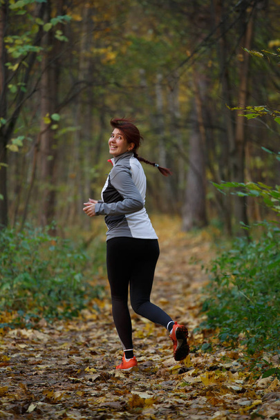 Photo of happy woman in sports clothes on run in autumn - Valokuva, kuva