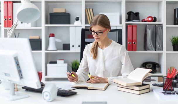 schönes junges Mädchen mit blonden Haaren. Ein Mädchen in weißer Bluse und schwarzer Hose arbeitet im Büro. Foto mit Schärfentiefe - Foto, Bild
