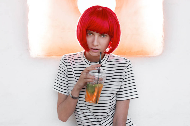 Portrait of a beautiful girl in a red wig drinking juice - Fotoğraf, Görsel