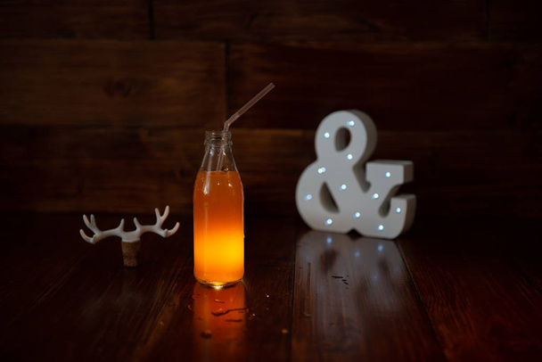una botella vintage de jugo recién exprimido sobre un fondo de madera y un ampersand brillante. Cerca de corcho de vino decorado con astas de ciervo
 - Foto, imagen