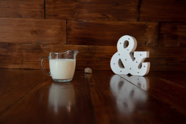 melk in glazen melkkannetje en een gloeiende ampersand - Foto, afbeelding